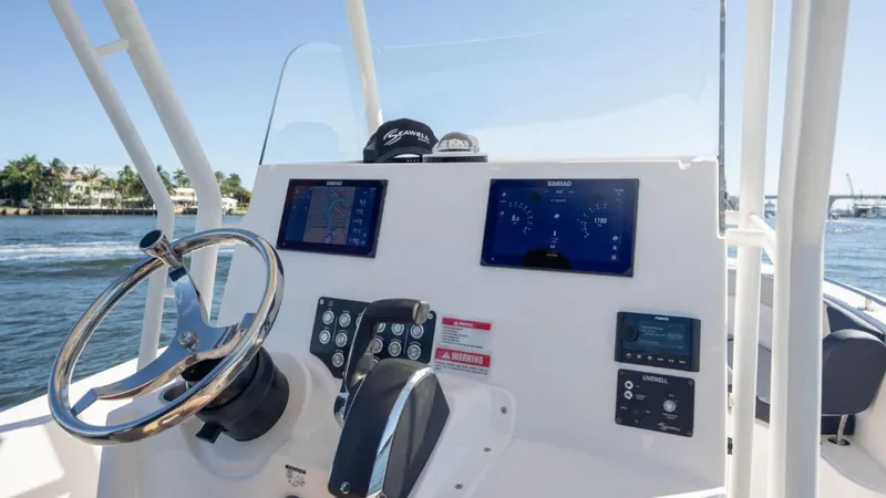 Slide: The Image of 2024 SeaWell 240CC boat dashboard with steering wheel and digital displays on open water. - 33