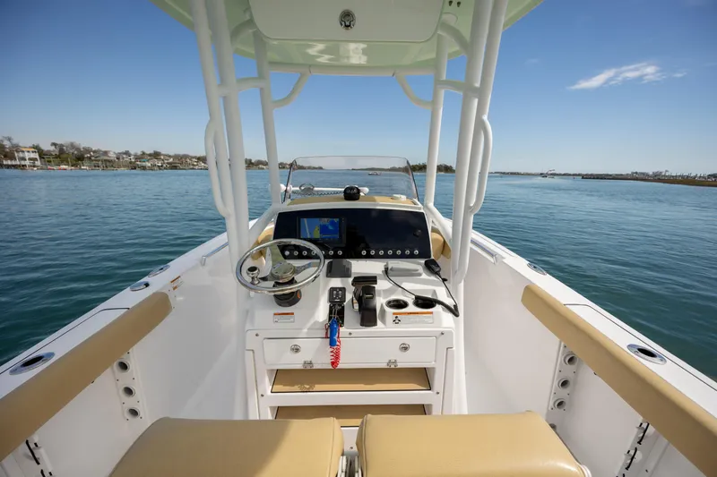 Slide: The Image of 2021 Sportsman Heritage 231 Center Console boat interior with steering wheel and controls on calm water. - 10