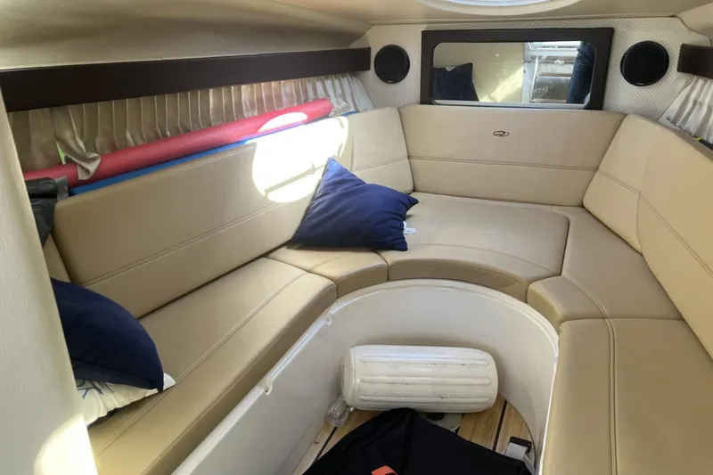 Slide: The Image of Interior of 2014 Regal 28 Express boat with beige seating and blue pillows. - 12