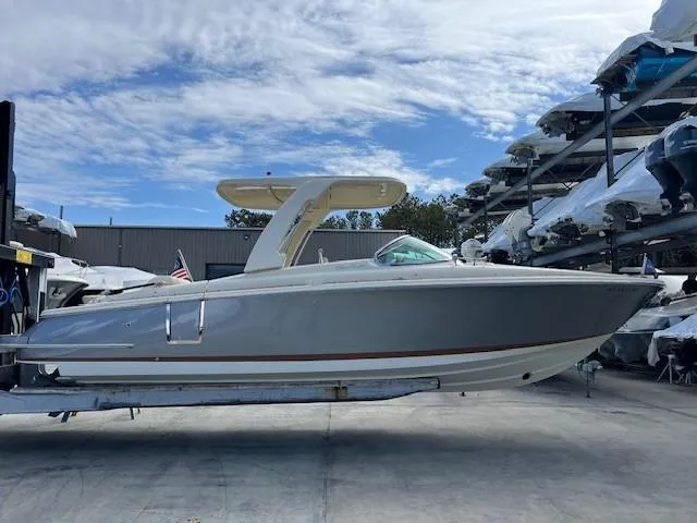 Slide: The Image of 2022 Chris-Craft Launch 28 GT boat in storage, side view under a partly cloudy sky. - 1