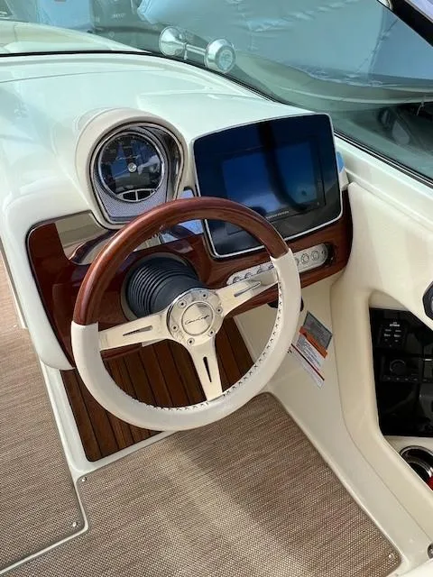 Slide: The Image of 2022 Chris-Craft Launch 28 GT dashboard with wooden steering wheel and modern controls. - 16