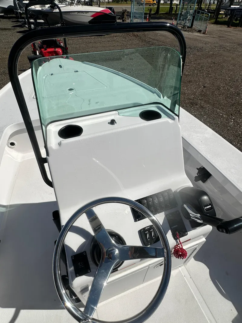 Slide: The Image of 2025 Action Craft 17 Flats Flyfisher boat console with steering wheel and windshield. - 17