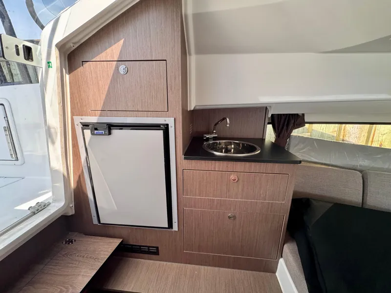 Slide: The Image of 2024 Beneteau Flyer 8 SUNdeck interior with kitchenette, sink, and compact fridge. - 13