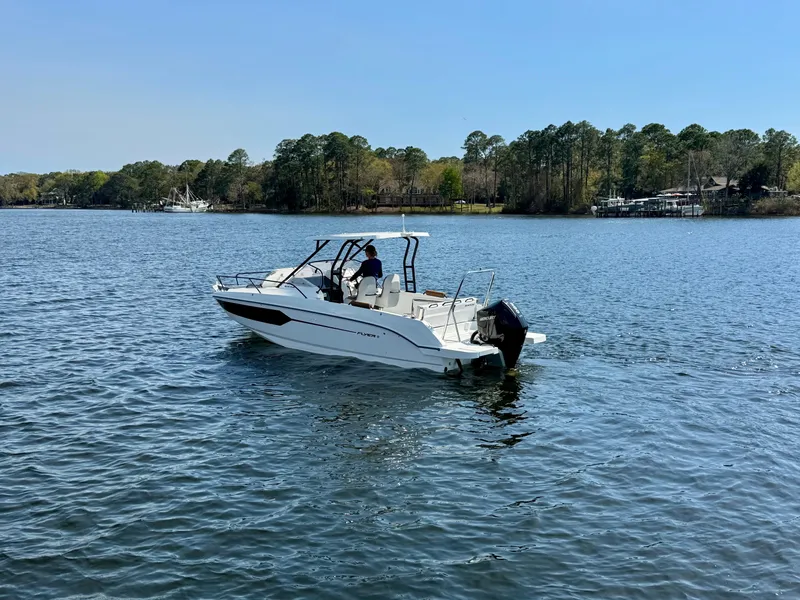 Slide: The Image of 2024 Beneteau Flyer 8 SUNdeck boat cruising on a serene lake with forested shoreline. - 9