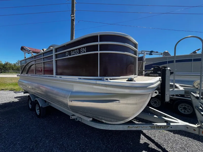 Slide: The Image of 2019 Bennington SX20 SFX pontoon boat on trailer, parked outdoors under clear blue sky. - 0