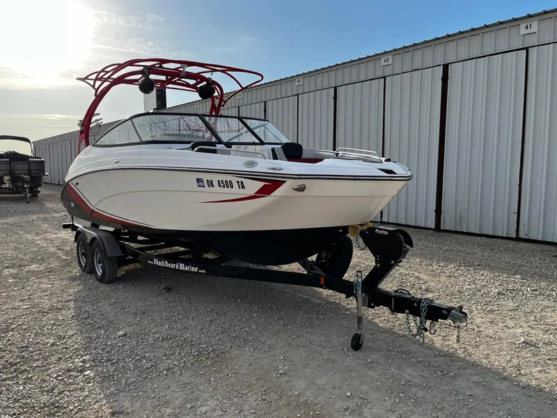 Slide: The Image of 2018 Yamaha Boats 242X E-Series on trailer, parked near storage units. - 1