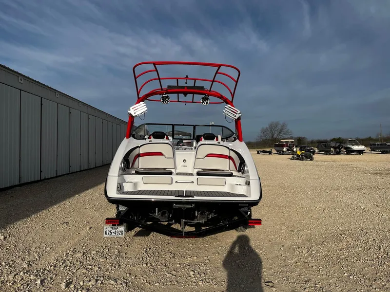 Slide: The Image of 2018 Yamaha Boats 242X E-Series, rear view, parked on gravel lot under clear sky. - 5