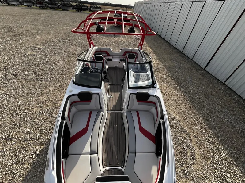 Slide: The Image of 2018 Yamaha Boats 242X E-Series with red accents and sleek design, parked on gravel. - 6