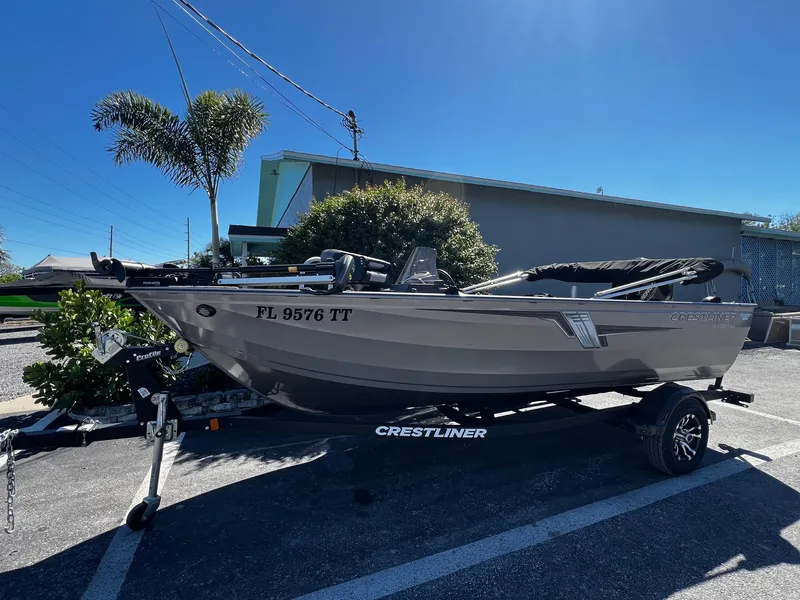 Slide: The Image of 2023 Crestliner 1600 Vision boat on trailer, parked outdoors under clear blue sky. - 0