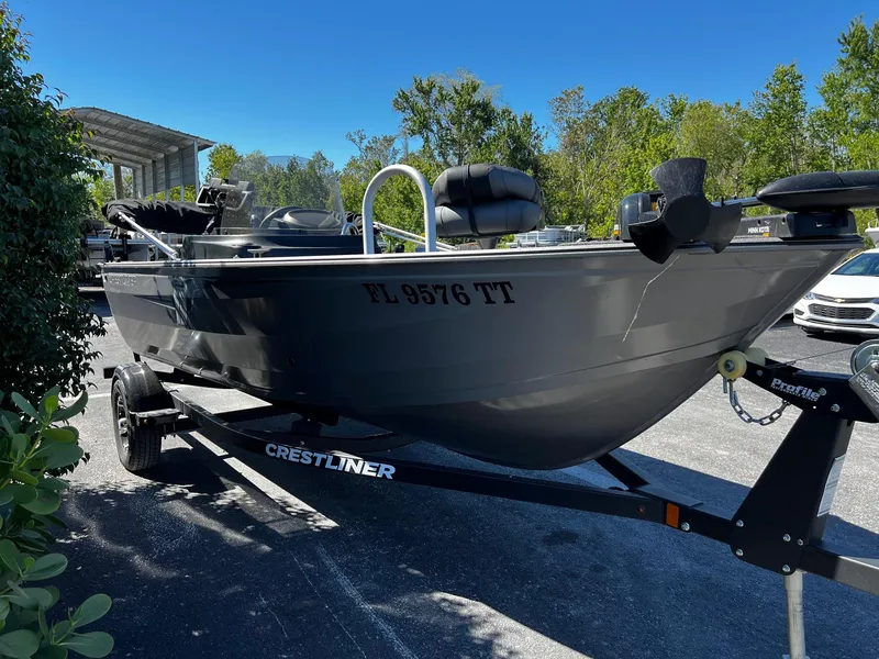 Slide: The Image of 2023 Crestliner 1600 Vision boat on trailer, parked outdoors under clear blue sky. - 2