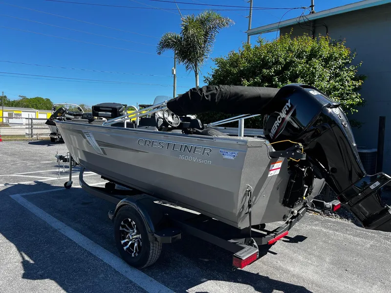Slide: The Image of 2023 Crestliner 1600 Vision boat on trailer, parked outdoors under clear blue sky. - 4
