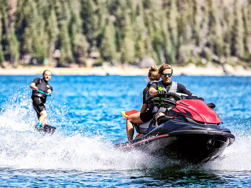 Slide: The Image of 2025 Kawasaki Jet Ski STX 160LX towing a wakeboarder on a scenic lake. - 16