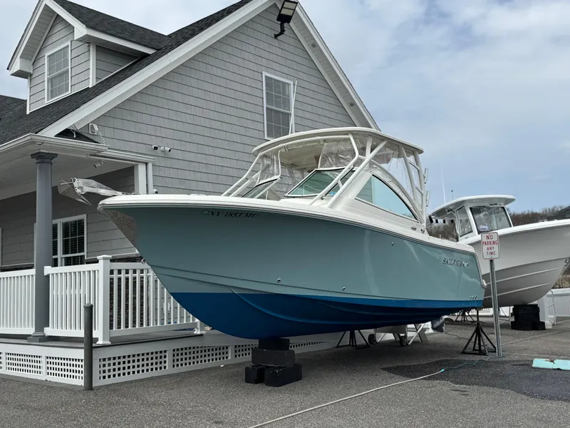 Slide: The Image of 2019 Sailfish 245 DC boat displayed outside a gray house. - 0
