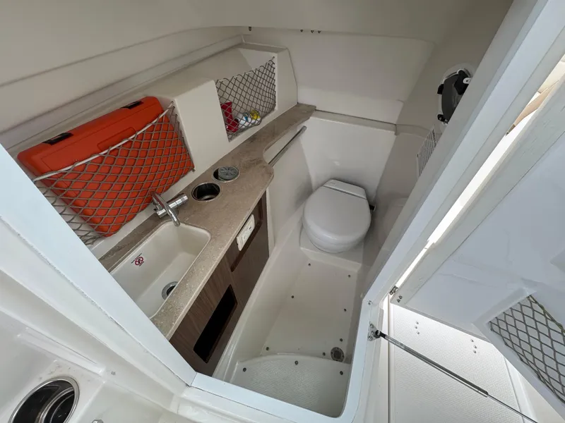 Slide: The Image of 2019 Sailfish 245 DC boat interior with sink, toilet, and storage compartments. - 14