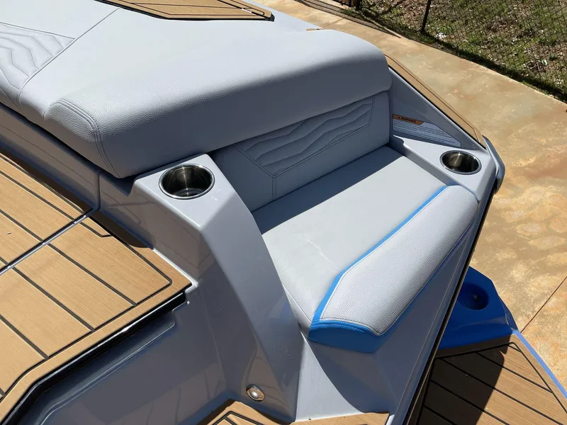 Slide: The Image of 2025 Nautique Super Air Nautique G25 boat seating area with cup holders and cushioned seats. - 12