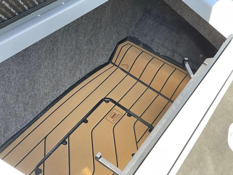 Slide: The Image of Storage compartment of 2025 Nautique Super Air Nautique G25 boat, featuring carpeted interior. - 15