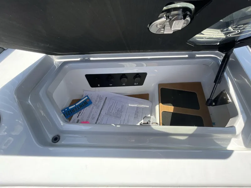 Slide: The Image of 2025 Nautique Super Air Nautique G25 storage compartment with documents and controls. - 19