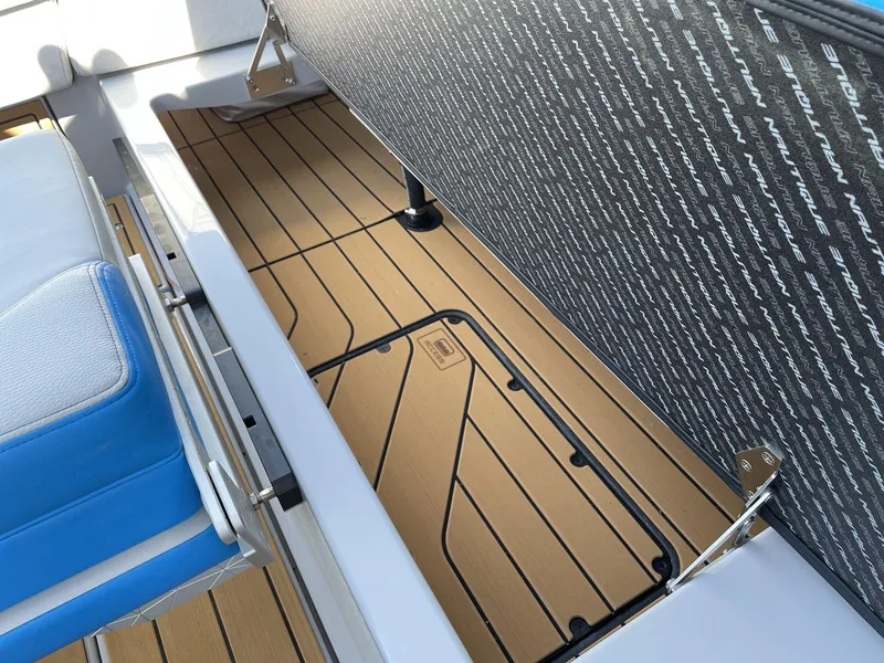 Slide: The Image of 2025 Nautique Super Air Nautique G25 interior storage with cushioned seating and teak-style flooring. - 24