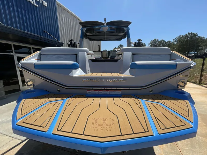 Slide: The Image of 2025 Nautique Super Air Nautique G25 boat, rear view, showcasing teak deck and centennial edition logo. - 6