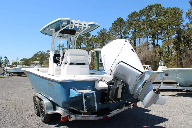 Slide: The Image of 2025 Tidewater 2500 Carolina Bay boat with outboard motor on trailer, parked outdoors. - 2