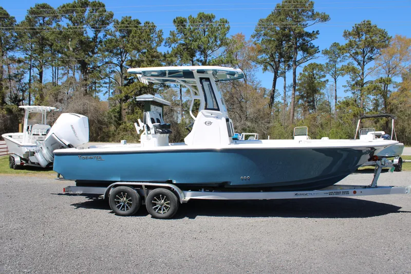 Slide: The Image of 2025 Tidewater 2500 Carolina Bay boat on trailer, parked outdoors with trees in background. - 28