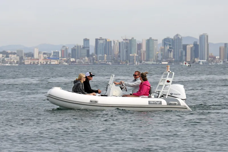 Slide: The Image of Four people on a 2025 Tide Craft Catalina 13 boat with city skyline in background. - 2