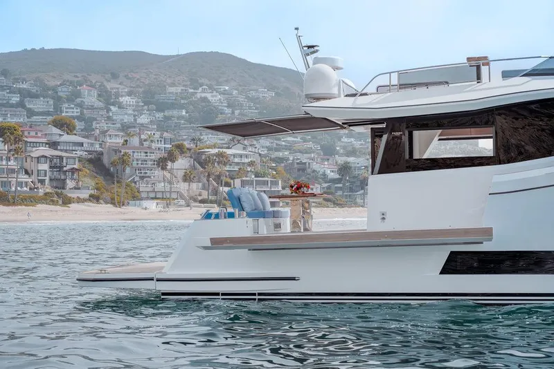 Slide: The Image of 2023 Pardo Yachts Endurance 60 cruising near a coastal town with hillside homes. - 13