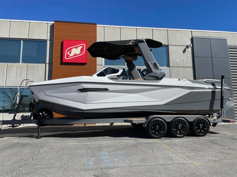 Slide: The Image of 2024 Nautique Super Air Nautique G25 Paragon boat on trailer, parked outside a building. - 1