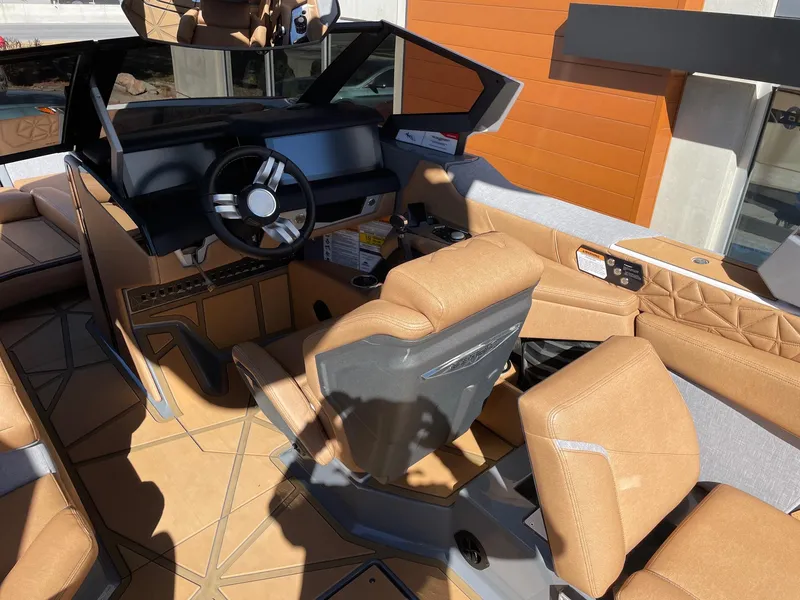 Slide: The Image of 2024 Nautique Super Air Nautique G25 Paragon interior with tan seating and modern dashboard. - 7
