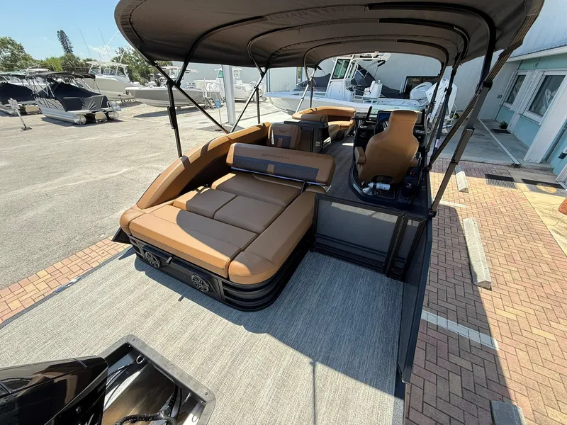 Slide: The Image of 2025 Bennington 24 MSB pontoon boat with tan seating and canopy, docked at marina. - 4