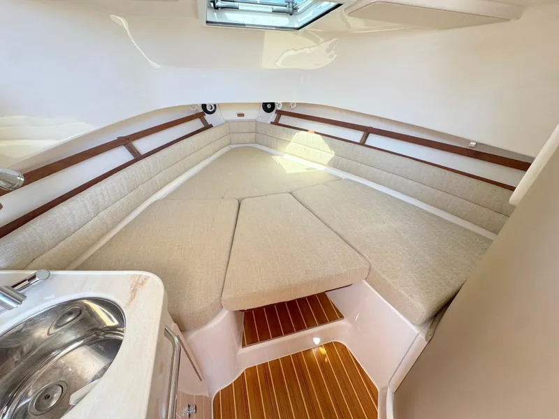 Slide: The Image of 2022 Grady-White Marlin 300 cabin interior with beige seating and wooden flooring. - 13