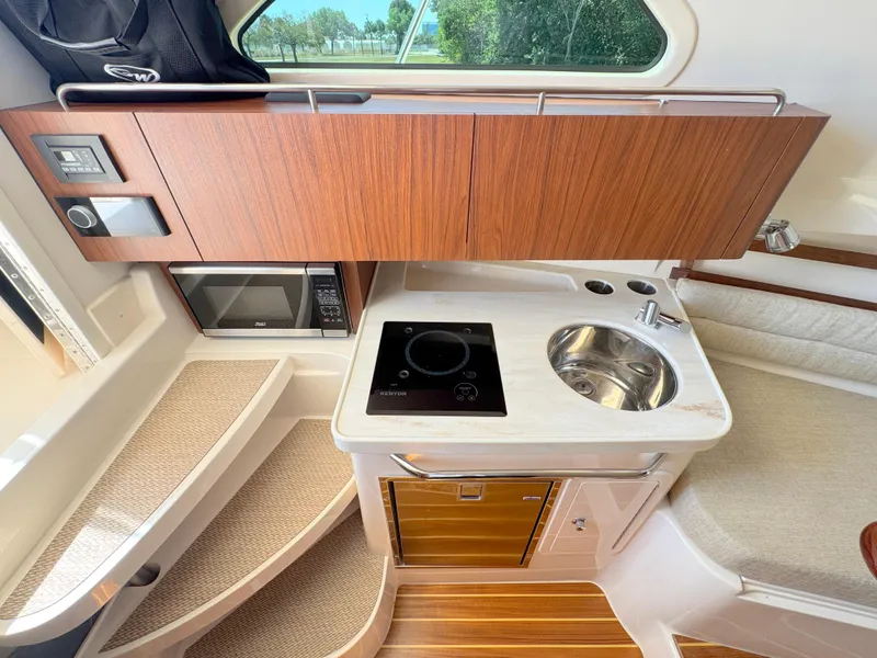 Slide: The Image of 2022 Grady-White Marlin 300 boat interior with kitchenette, featuring stove, sink, and microwave. - 15