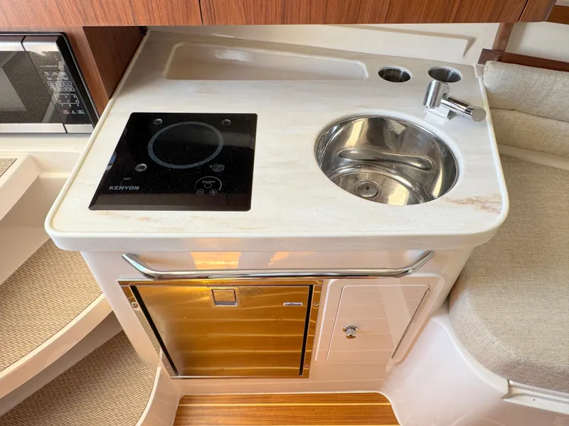 Slide: The Image of 2022 Grady-White Marlin 300 boat galley with sink, stove, and compact fridge. - 16