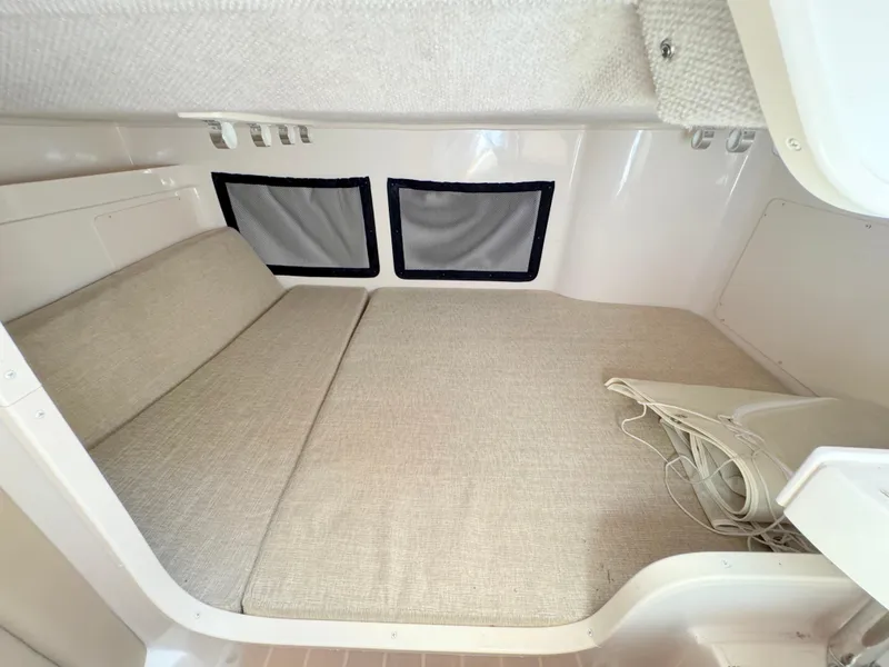 Slide: The Image of 2022 Grady-White Marlin 300 cabin interior with beige cushions and windows. - 21