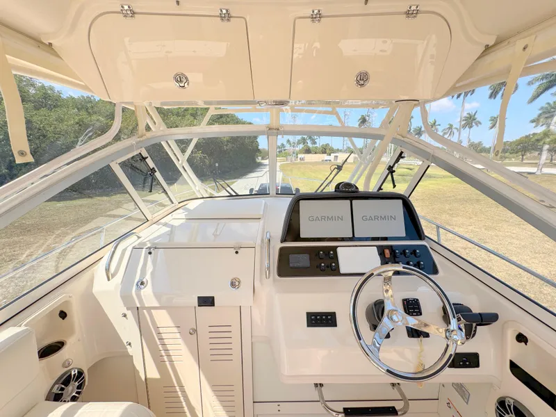 Slide: The Image of 2022 Grady-White Marlin 300 helm with Garmin navigation, steering wheel, and spacious cockpit view. - 28