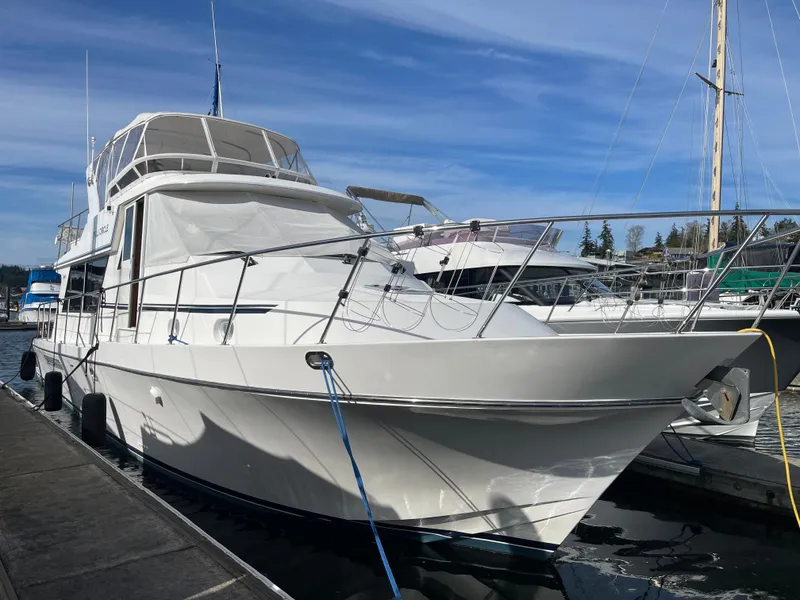 Slide: The Image of 2002 Canoe Cove 50 Pilothouse Luxury Yacht docked at marina under clear blue sky. - 0