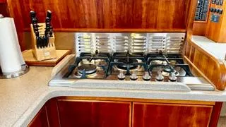 Slide: The Image of Luxury yacht kitchen with gas stove, wooden cabinetry, and knife set on Canoe Cove 50 Pilothouse. - 12
