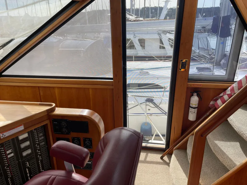 Slide: The Image of Interior view of 2002 Canoe Cove 50 Pilothouse Yacht, featuring helm and marina backdrop. - 16