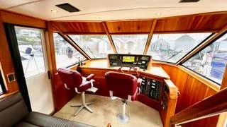 Slide: The Image of Pilothouse interior of 2002 Canoe Cove 50 Pilothouse Luxury Yacht with red chairs and control panel. - 2