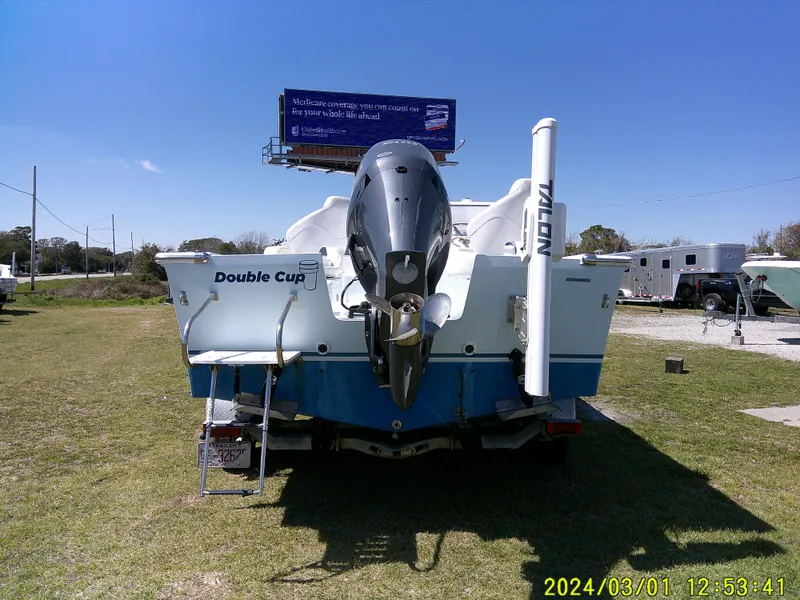 Slide: The Image of Southern Cross 23 boat, rear view, parked on grass, with outboard motor, sunny day. - 10