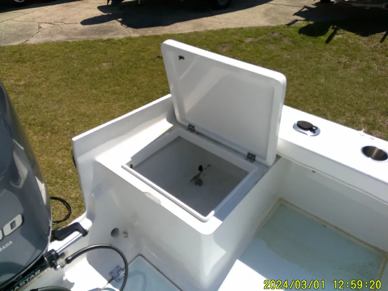 Slide: The Image of Open storage compartment on a 2020 Southern Cross 23 boat, with visible engine and grass background. - 37