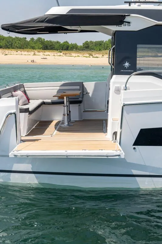 Slide: The Image of 2025 Jeanneau NC 1295 Coupe yacht with sleek deck design, anchored near a sandy beach. - 13