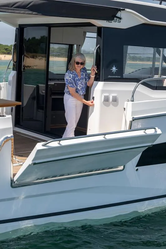 Slide: The Image of 2025 Jeanneau NC 1295 Coupe yacht with person on deck, open side panel, sunny day. - 15