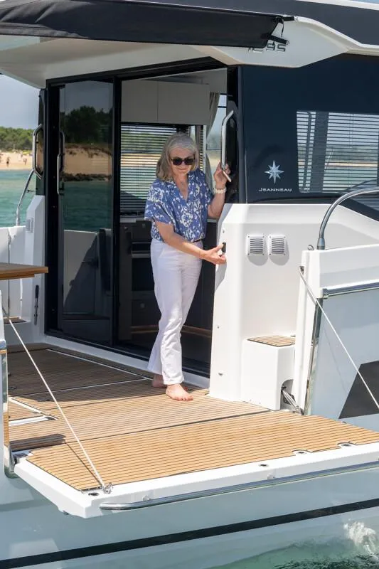 Slide: The Image of Woman on Jeanneau NC 1295 Coupe 2025 yacht, standing on deck near cabin entrance. - 16