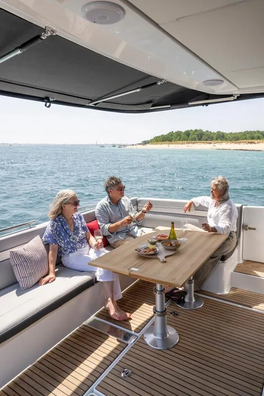 Slide: The Image of People relaxing on a 2025 Jeanneau NC 1295 Coupe yacht, enjoying a meal. - 47