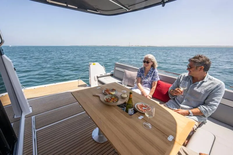 Slide: The Image of Couple enjoying a meal on the Jeanneau NC 1295 Coupe yacht, 2025 model, with ocean view. - 49
