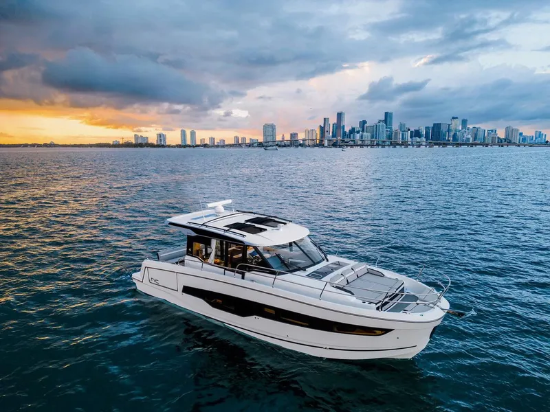 Slide: The Image of 2025 Jeanneau NC 1295 Coupe yacht cruising near city skyline at sunset. - 8