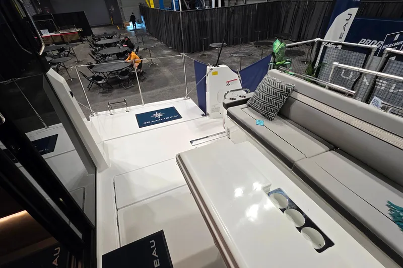 Slide: The Image of 2026 Jeanneau NC 1295 Coupe boat interior with seating and table at a show. - 86