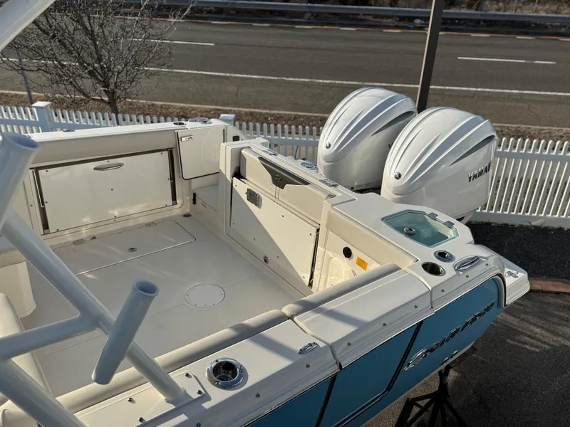 Slide: The Image of 2024 Sailfish 276 DC boat with dual outboard engines, docked near a road. - 2