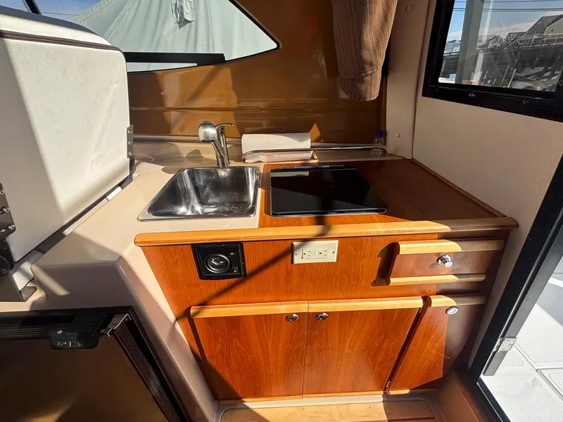 Slide: The Image of 2017 Cutwater C-242 Sport Coupe interior kitchen with sink, stove, and wooden cabinetry. - 17